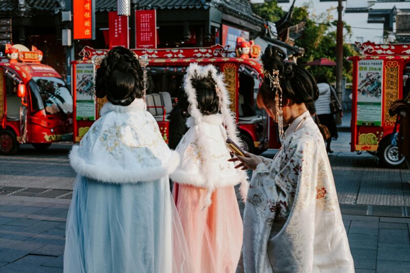 Women in traditional Chinese attire walking through a lively Nanjing street with colorful decorations.